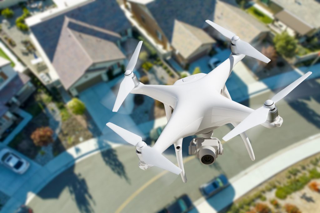 Industry-Unmanned Aircraft System Quadcopter Drone In The Air Over Residential Neighborhood.